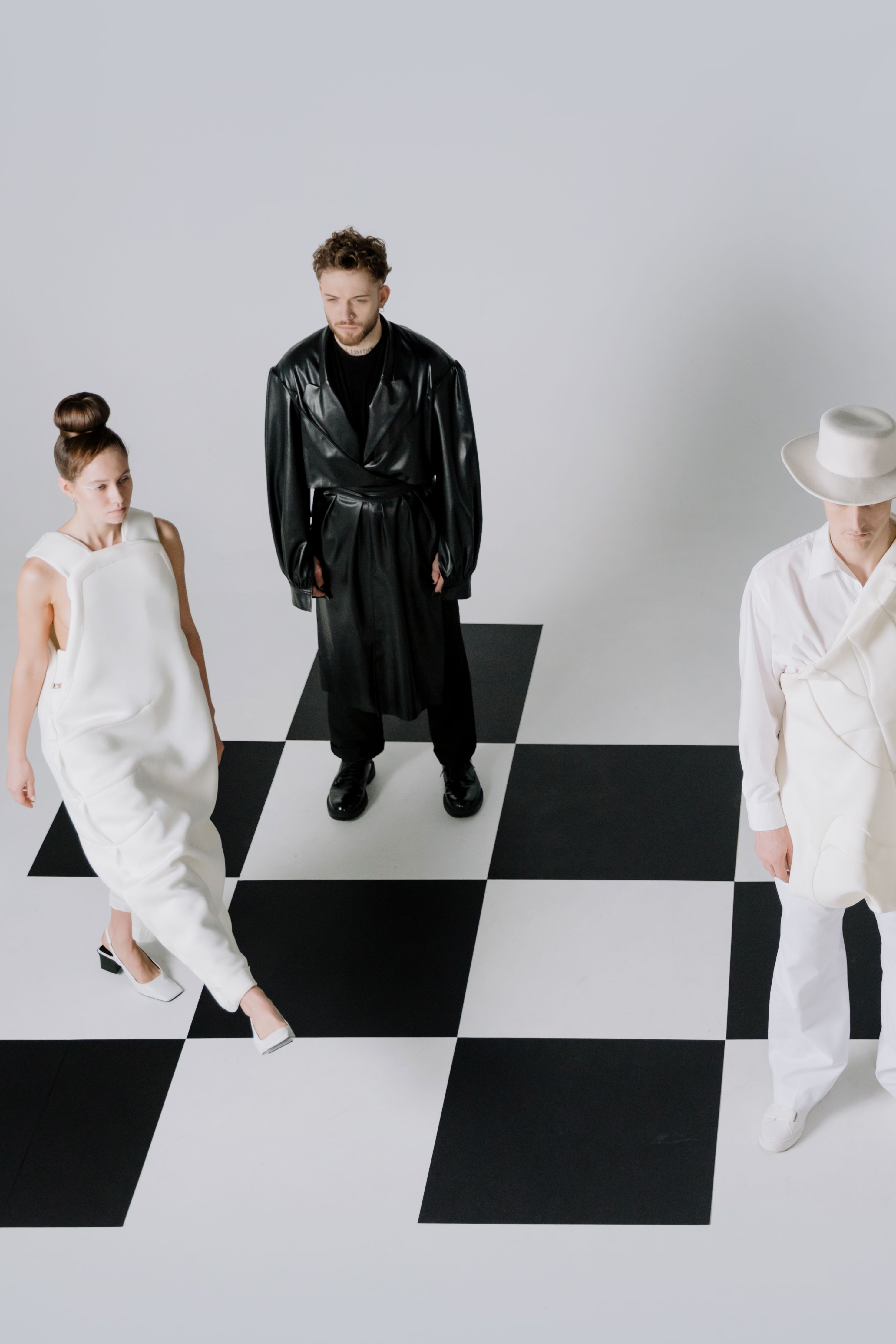 Modenschau: drei Models in Designer-Outfits auf einem Schachbrettboden